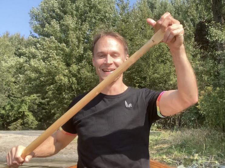 Ken sitting in his handmade wooden canoe, paddling on a lake near Ann Arbor, Michigan.