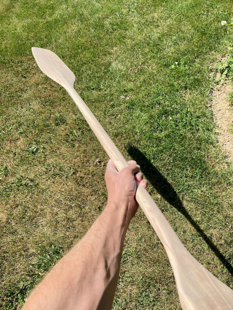 holding my hand-carved otter tail paddle