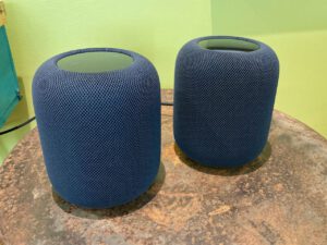 two Apple HomePods on a rusty coffee table