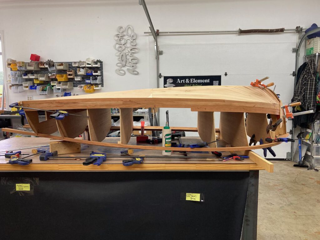 Wooden boat under construction. Various clamps on the bow and stern as strips transition from one face to another.