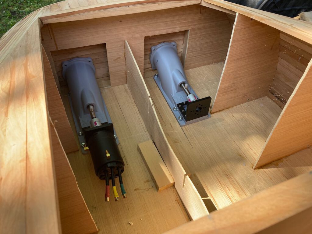 A view inside the stern of the wooden boat under construction. The two jets are fitted in place, one with an electic motor installed.