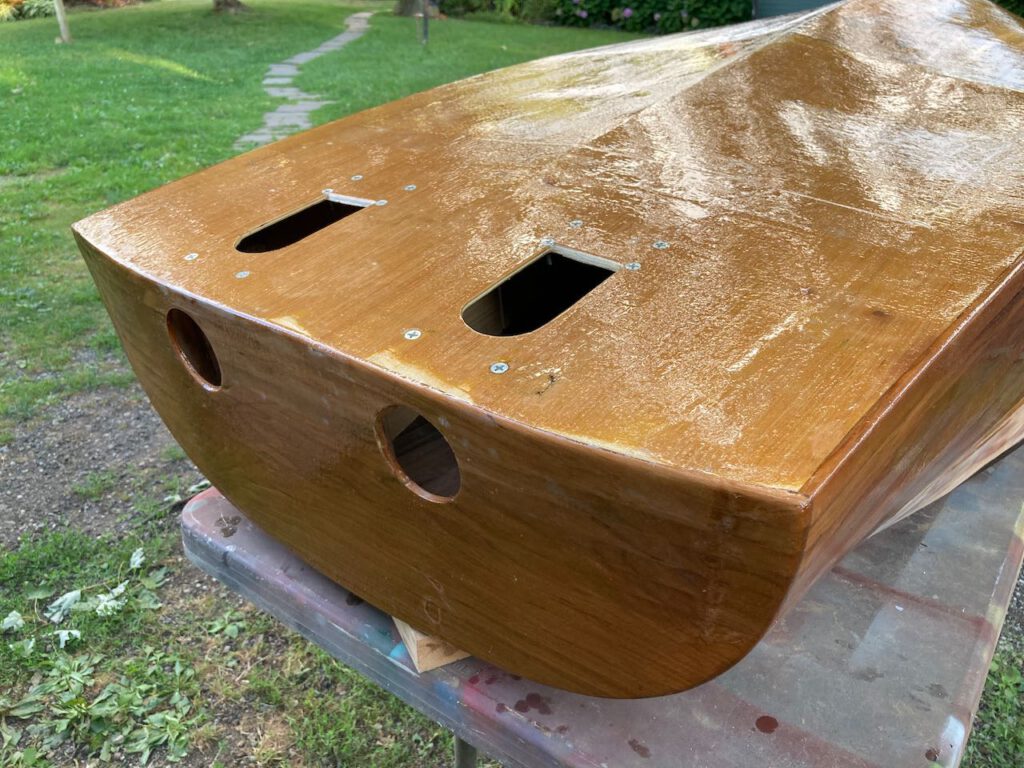 Fiberglass and epoxy line the bottom and stern of this boat, upside down on a table outdoors. Cut outs are ready to receive propulsion jets.