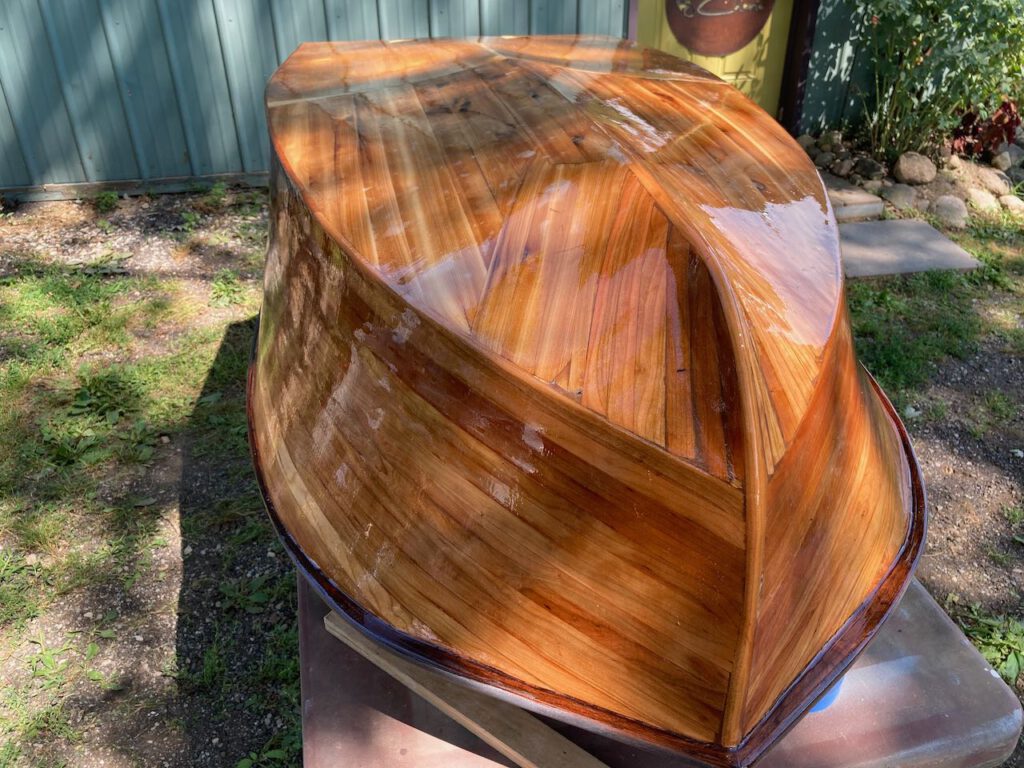 A wooden boat, upside down, after one of the final coats of epoxy resin.